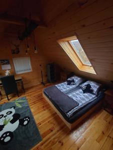 a bedroom with a bed and a window in a attic at Domek Tuni in Pewel Wielka