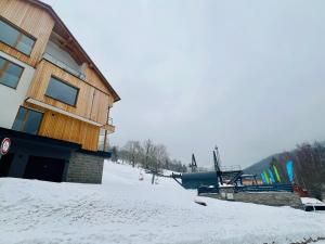 a ski lodge with snow on the ground next to a building at Golden Ridge Apartments in Špindlerův Mlýn