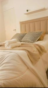 Una cama con sábanas blancas y almohadas. en Casa Deco con Pileta, Asador y Cochera en Córdoba