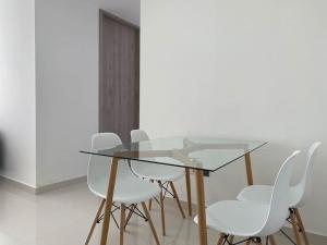 una mesa de cristal y sillas blancas en una habitación en Nuevo a 10 minutos de Buenavista, en Puerto Colombia