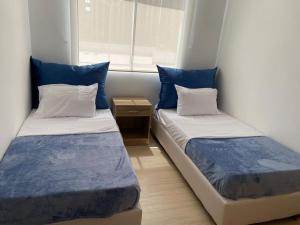 2 camas en una habitación pequeña con almohadas azules en Nuevo a 10 minutos de Buenavista, en Puerto Colombia