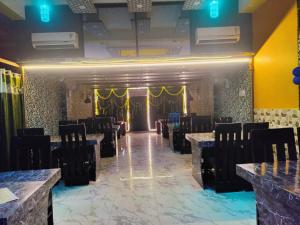 a banquet hall with black chairs and a stage at Hotel Shivaay Inn in Patna