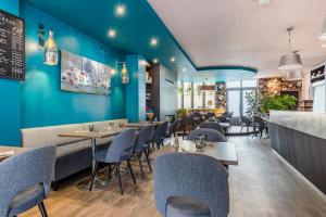 a restaurant with blue walls and tables and chairs at Hotel-Restaurant Le Victoria in Rennes