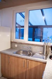eine Küche mit einem Waschbecken und zwei großen Fenstern in der Unterkunft Gaston vakantiehuis in Geraardsbergen