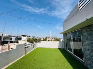 a balcony with green grass on the side of a building at Home Escape Luxe 2BHK Penthouse Near LIG Square in Indore