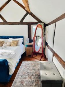 a bedroom with a bed and a mirror in it at Log Burner and Beamed Ceilings-2 Bed Cottage Crumpelbury and Whitbourne Hall less than a 4 minute drive Dog walking trails and local pub within walking distance and a 30 minute drive to the Malvern Hills in Worcester
