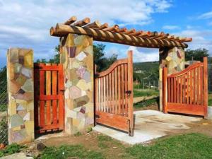 um portão de madeira com um arco de pedra com um telhado em Cabaña Lijeron #1 em Samaipata