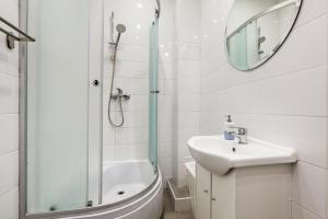a bathroom with a shower and a sink and a mirror at Prime Home CENTRUM 2 in Gdynia