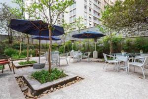 un patio con tavoli, sedie e ombrelloni di B Homy Itaim - Condomínio completo GEO206 a San Paolo