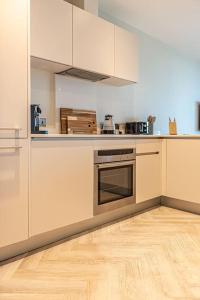 a kitchen with white cabinets and a wooden floor at Luxurious 2 Bed - RIVER VIEW in Liverpool