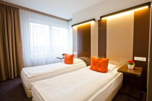 two beds in a hotel room with orange pillows at Platinum Apartments Aparthotel in Poznań