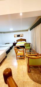a bedroom with two beds and chairs in a room at Hotel Laureles 70 in Medellín