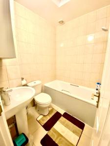 uma casa de banho com uma banheira, um WC e um lavatório. em Spacious Ground Floor Two Bedroom house on in Ealing London em Ealing