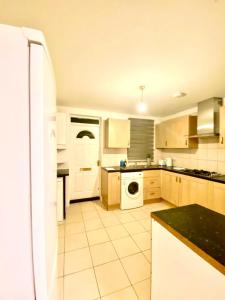 uma cozinha com armários brancos e um aparelho branco em Spacious Ground Floor Two Bedroom house on in Ealing London em Ealing