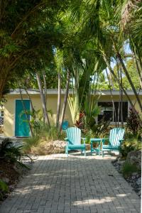 two blue chairs sitting on a patio with palm trees at Coconut Bay Resort - Key Largo in Key Largo