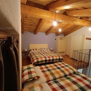 2 łóżka w pokoju z drewnianym sufitem w obiekcie 'L ciabot 'd Ginota w mieście Barge