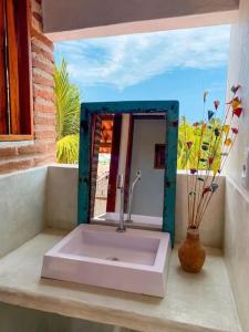 a bathroom sink with a mirror and a vase at Apartamento Floreal in Amontada