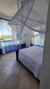 a bedroom with a white bed with a canopy at Wanderstay Vacation Homes in Malindi