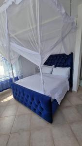 a blue bed with a canopy in a room at Wanderstay Vacation Homes in Malindi
