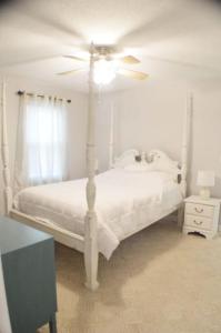 um quarto com uma cama branca e uma ventoinha de tecto em Cozy Family Retreat with Spa Bath Fenced Yard em New Bern