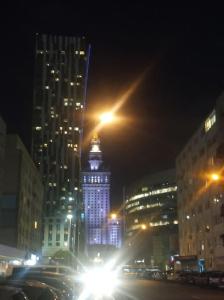 a tall building with lights in a city at night at City Center-Złota str. in Warsaw