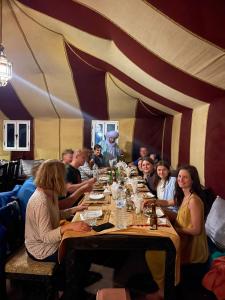 a group of people sitting around a table in a restaurant at Your Family Camp in Merzouga