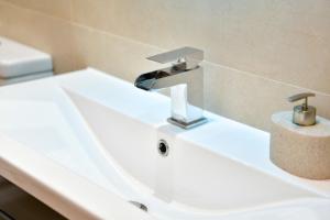 a white bathroom sink with a faucet on it at 5* Hotel Quality-10Min From City in Cardiff