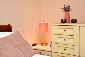 a bedroom with a bed with a lamp on a dresser at 5* Hotel Quality-10Min From City in Cardiff