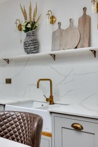 a kitchen with a sink and a counter with a chair at Luxury Georgian Townhouse with Cinema and parking in Chester +22 photos
