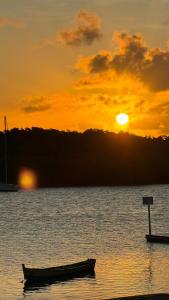 a boat sitting in the water at sunset at Aloha Suites in Barra de São Miguel