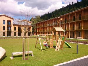 uma criança a brincar num parque infantil em frente a um edifício em Apartmán Medvědín 110 em Spindleruv Mlyn