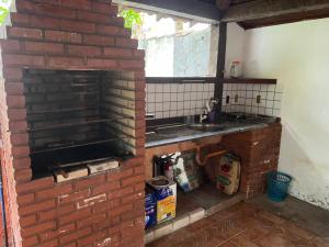 a kitchen with a brick fireplace and a sink at Praia e Churrasco em Búzios in Búzios