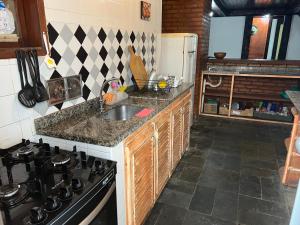 a kitchen with a sink and a stove at Praia e Churrasco em Búzios in Búzios