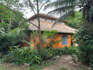 an orange house in the middle of a forest at Praia e Churrasco em Búzios in Búzios