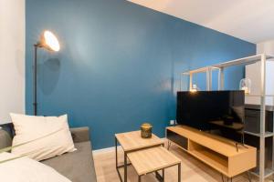 ein Wohnzimmer mit einem Sofa und einer blauen Wand in der Unterkunft Studio Cosy à 15min de Paris et 5min du Métro in La Courneuve