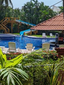 uma piscina no resort com cadeiras e um escorrega em Apartamento Colibrí em Ixtapa