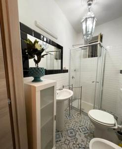 a bathroom with a toilet and a sink and a vase of flowers at Igea Suite in Noto