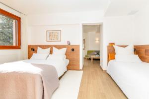 2 camas en una habitación con paredes blancas en Ginkgo - Familienfreundliches Appartment in Katalanischer Masia, en Sant Iscle de Vallalta