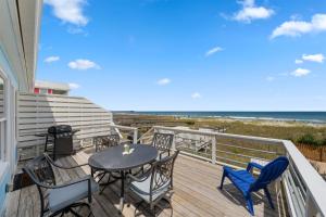 ein Balkon mit Tisch und Stühlen und der Strand in der Unterkunft Ocean Oasis Kure Beach Ocean front, Pool coming soon! in Kure Beach