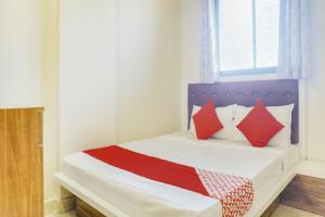 a bedroom with a bed with red pillows and a window at OYO Hotel Vijay Residency in Bangalore