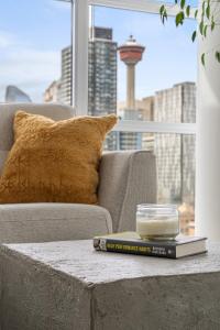 a book on a coffee table in front of a couch at Luxury Corner Unit w Panoramic Tower & Downtown Skyline Views! FREE Banff Pass, Wine, Gym & Parking! in Calgary