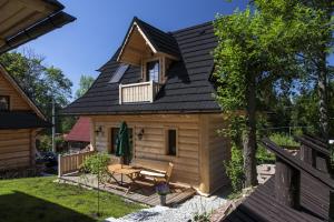 a log cabin with a gambrel roof and a porch at Maki Domki Regionalne in Witów