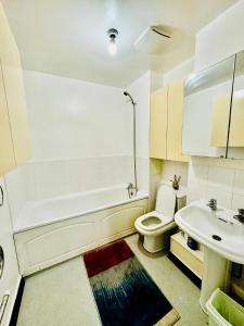 ein Badezimmer mit einer Badewanne, einem WC und einem Waschbecken in der Unterkunft Luxury 2 beds Apartment with 2 bathrooms, living dining & Parking - East London in Barkingside