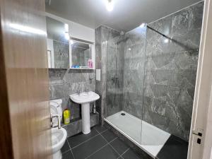 een badkamer met een douche, een toilet en een wastafel bij Luxury 2 beds Apartment with 2 bathrooms, living dining & Parking - East London in Barkingside