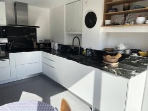 a kitchen with white cabinets and a black counter top at Résidence -pleneuf Val Andre - Maisons & Villas 604 in Pléneuf-Val-André