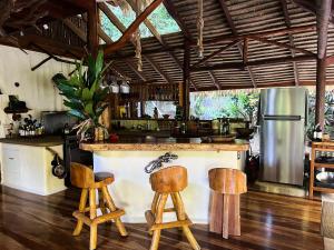 a kitchen with a bar with two wooden stools at Casa Vida Verde in Cabo Matapalo