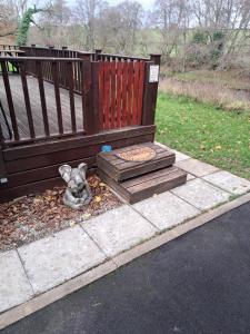 un piccolo cane seduto per terra accanto a una panchina di Bunny Lodge 30 - Riverside a Builth Wells