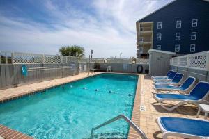 a swimming pool with blue chairs and a building at Beachy Condo right on Oceanfront in Myrtle Beach
