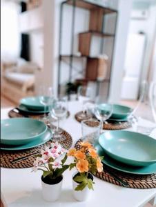 - une table avec des assiettes, des verres et des fleurs dans l'établissement Plage & Confort Appartement 3 pièces Parking clim et wifi, à Antibes
