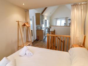 a bedroom with a white bed and a kitchen at The Loft Cottage in Totnes